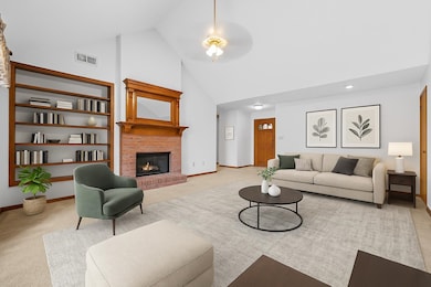 As you step through the gracious entryway, you're greeted by a spacious vaulted great room featuring built-in bookshelves, and a cozy fireplace for chilly evenings. This is a virtually staged photo to show the room's potential.