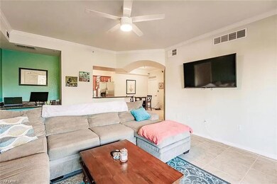 Living room with arched walkways, ornamental molding, ceiling fan, and tile patterned flooring