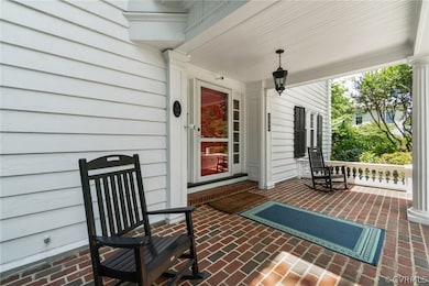 Covered, brick front porch overlooking the Magnolia tree and circular drive