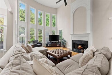 Living area with a high end fireplace, a ceiling fan, wood finished floors, and a high ceiling