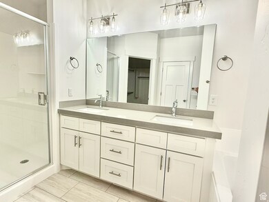 Full bathroom with double vanity, a shower stall, and light tile patterned floors