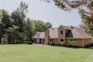 Rear view of property featuring a patio, a yard, brick siding, and a chimney