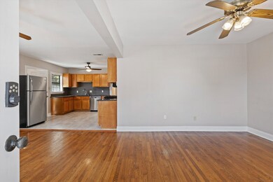 Kitchen featuring a ceiling fan, stainless steel appliances, brown cabinetry, light wood-type flooring, and tasteful backsplash