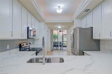 Kitchen featuring appliances with stainless steel finishes, white cabinetry, light stone countertops, and ornamental molding