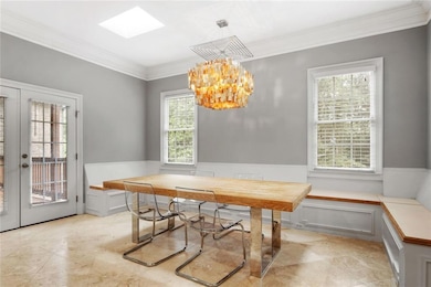 Dining area with crown molding, french doors, a chandelier, and wainscoting