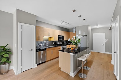 Kitchen with appliances with stainless steel finishes, dark countertops, decorative backsplash, and light wood-style flooring