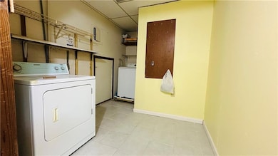 Laundry room featuring washing machine and dryer, baseboards, and light tile patterned floors