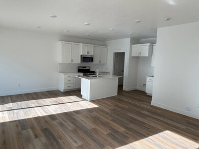 Kitchen with open floor plan, white cabinets, dark wood-style floors, a kitchen island with sink, and stainless steel appliances