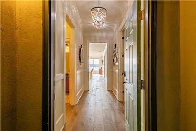 Corridor featuring wood finished floors, ornamental molding, and a chandelier