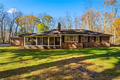 The back of the home has an enclosed patio overlooking the stunning lot with the sounds of the trees and creek