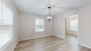 Empty room with an inviting chandelier, light wood