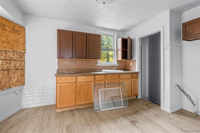 Kitchen featuring light wood finished floors, tasteful backsplash, a textured ceiling, and dark countertops