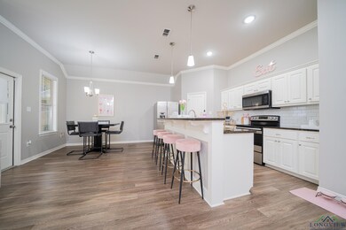 Kitchen with stainless steel appliances, ornamental molding, a kitchen bar, wood finished floors, and dark countertops