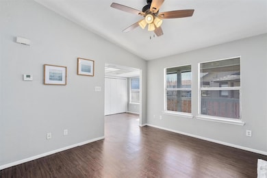 Spare room featuring lofted ceiling, dark wood-style floors, and a ceiling fan