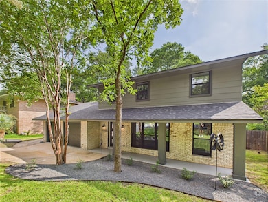 View of front facade featuring a shingled roof, brick siding, a garage, and driveway