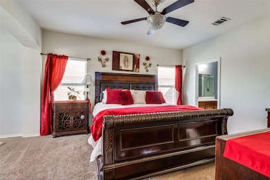 Carpeted bedroom featuring ceiling fan and connected bathroom