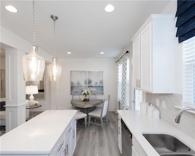 Kitchen featuring dishwasher, light countertops, light wood-style floors, decorative backsplash, and recessed lighting