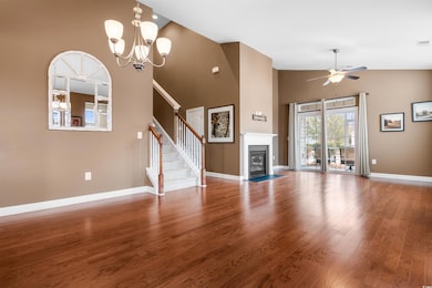 Unfurnished living room with hardwood / wood-style floors, ceiling fan with notable chandelier, and a towering ceiling