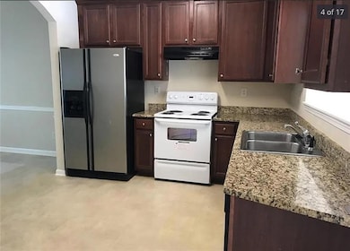 Kitchen featuring stainless steel fridge, arched walkways, white range with electric stovetop, a sink, and exhaust hood