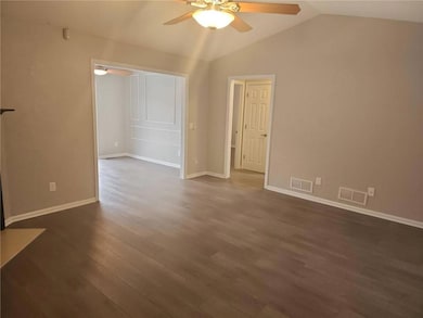 Unfurnished living room featuring ceiling fan, lofted ceiling, and dark wood-style flooring