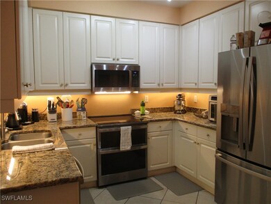Kitchen featuring appliances with stainless steel finishes, light tile patterned flooring, sink, and white cabinets