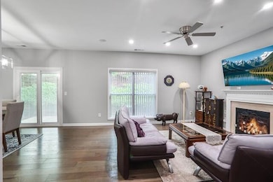Living area featuring plenty of natural light, wood finished floors, a ceiling fan, a warm lit fireplace, and recessed lighting