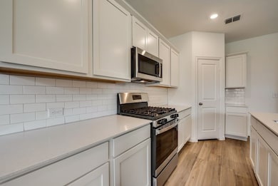 Kitchen with appliances with stainless steel finishes, light wood-style flooring, light countertops, recessed lighting, and tasteful backsplash