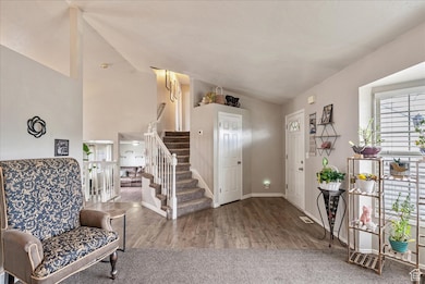 Foyer with vaulted ceiling, stairs, and wood finished floors