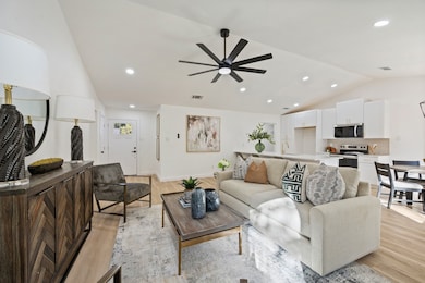 Living room with lofted ceiling, recessed lighting, light wood-style floors, and ceiling fan