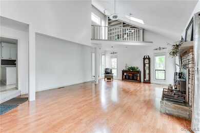 Living room with a skylight, a stone fireplace, hi