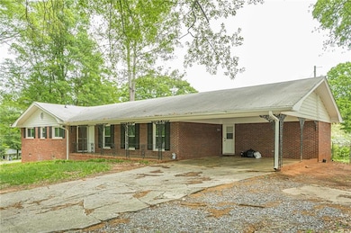 Single story home with driveway, brick siding, and a carport