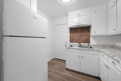 Kitchen with freestanding refrigerator, light countertops, white cabinetry, and light wood-style floors