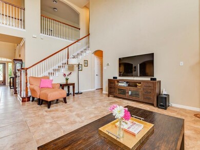 Living area featuring a towering ceiling, stairs, arched walkways, and light tile patterned floors