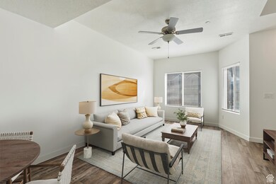 Living room featuring wood finished floors, a ceiling fan, and a textured ceiling. Staged