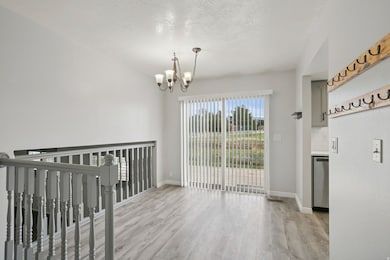 Unfurnished dining area with light wood-style floors, a textured ceiling, and a chandelier