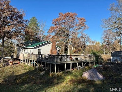 Rear view of house with a deck, a chimney, and view of scattered trees