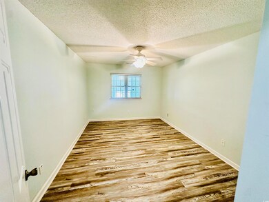 Empty room featuring a ceiling fan, a textured ceiling, and wood finished floors