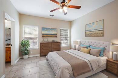 Tiled bedroom with multiple windows, ceiling fan, and ensuite bath