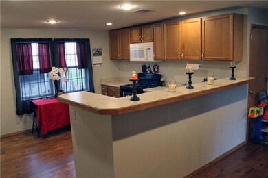 Kitchen with light countertops, brown cabinetry, black gas stove, dark wood-type flooring, and recessed lighting
