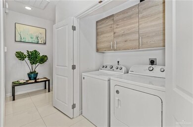 Laundry area with cabinets, independent washer and dryer, and light tile patterned flooring