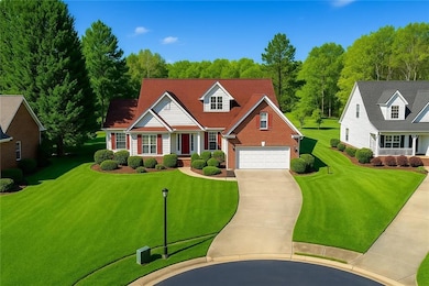 Cape cod-style house with brick siding, a garage, driveway, and a front yard