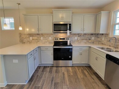 Ex: Kitchen w/ grey cabinets, tile backsplash, quartz countertops, stainless appliances