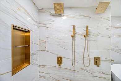 Bathroom with a marble finish shower, a soaking tub, and elevator