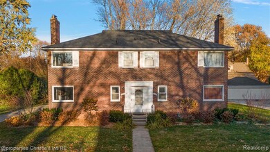 View of front of house with a chimney, a front yard, and brick siding