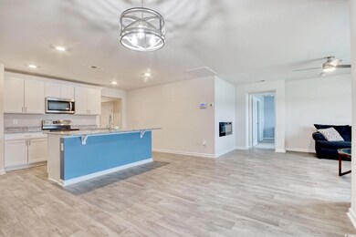 Kitchen with stainless steel appliances, open floor plan, a kitchen island with sink, a breakfast bar, and white cabinets