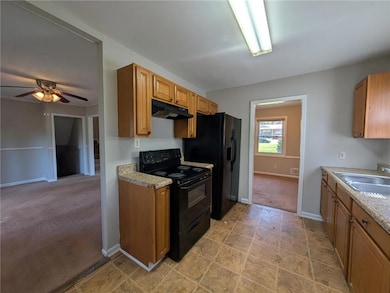 Kitchen with black appliances, a sink, under cabin