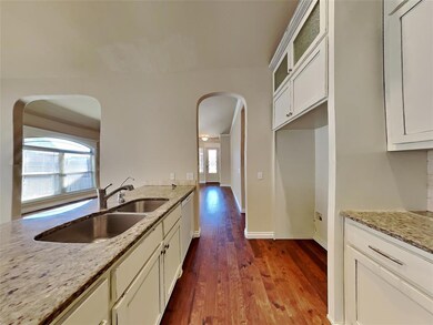 Kitchen with wood-type flooring, sink, light stone