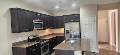 Kitchen featuring stainless steel appliances, stone counters, an island with sink, recessed lighting, and tile patterned flooring