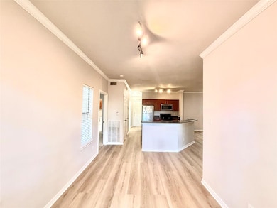 Kitchen featuring dark countertops, rail lighting, light wood-type flooring, freestanding refrigerator, and ornamental molding
