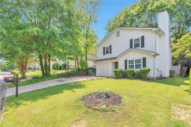 Traditional-style home with an attached garage, driveway, a chimney, and a front lawn